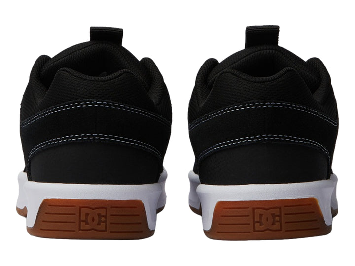 Tenis DC Shoes color negro con suela blanca y base café, vista lateral.
