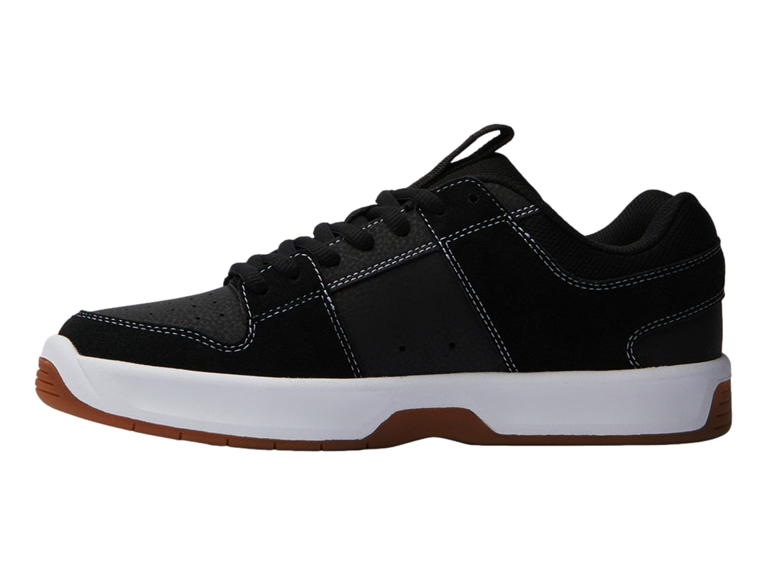 Tenis DC Shoes color negro con suela blanca y base café, vista lateral.