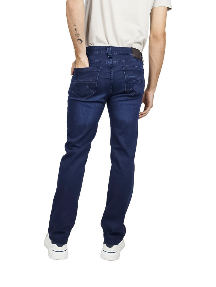Hombre vistiendo pantalones jeans azul oscuro de corte recto y tenis blancos.