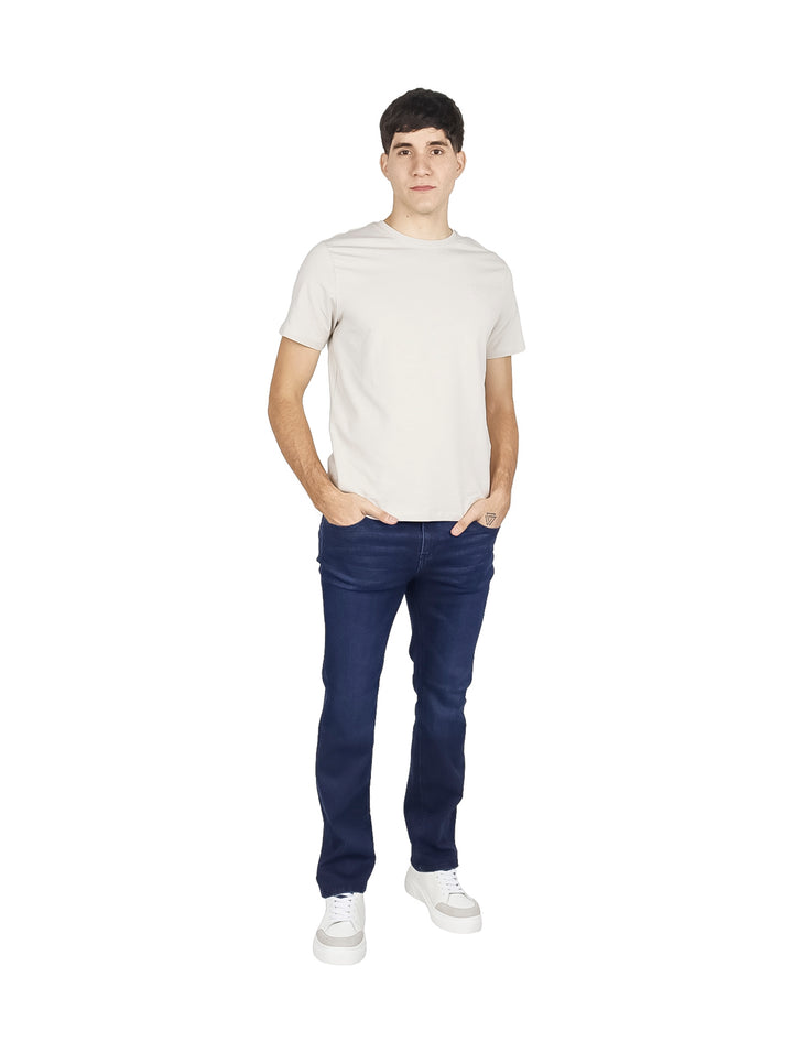 Hombre vistiendo pantalones jeans azul oscuro de corte recto y tenis blancos.