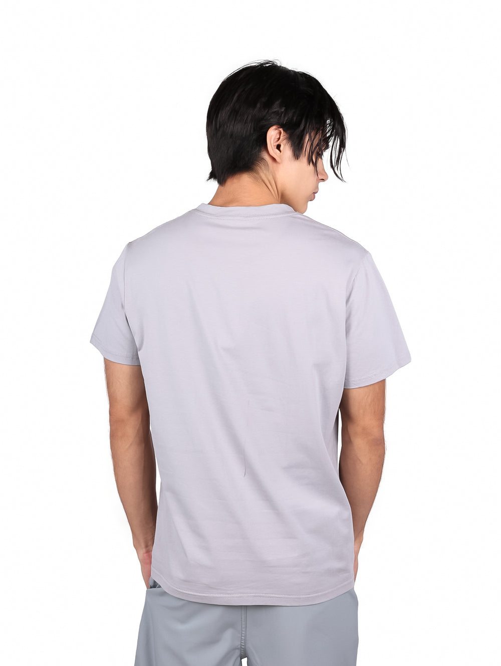Hombre vistiendo playera gris de manga corta con estampado de lentes de sol y texto en el pecho.