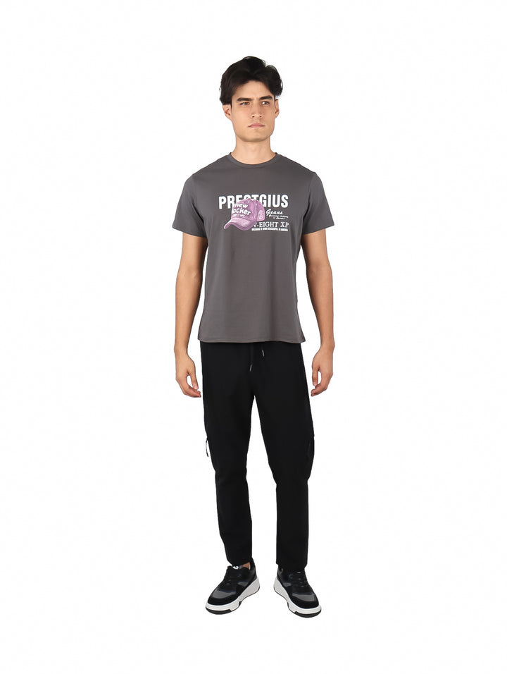Hombre vistiendo playera gris de manga corta con estampado gráfico de una gorra rosa y texto en el pecho.
