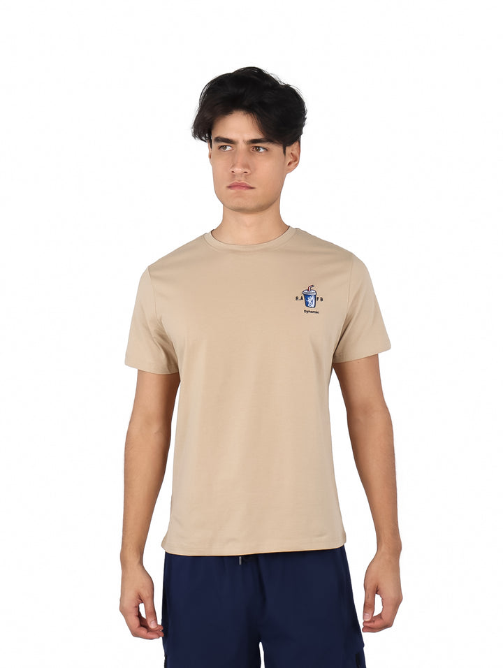 Hombre vistiendo playera de manga corta color café con logotipo pequeño en el pecho.
