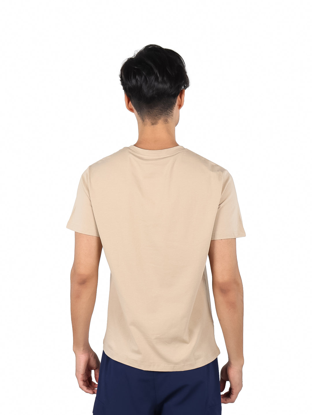 Hombre vistiendo playera de manga corta color café con logotipo pequeño en el pecho.
