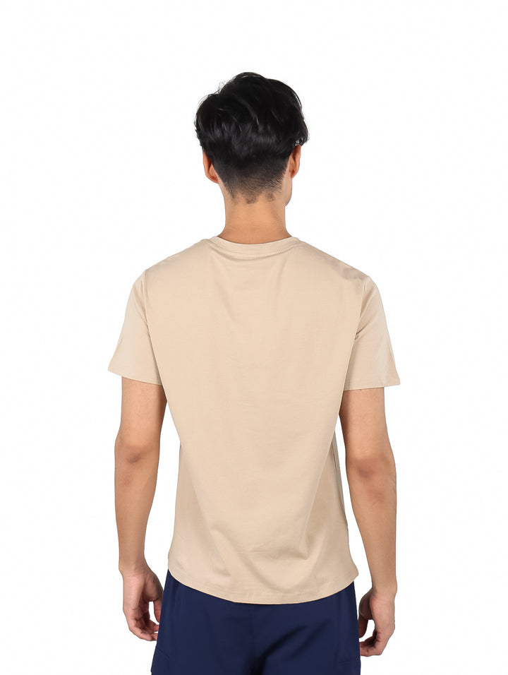 Hombre vistiendo playera de manga corta color café con logotipo pequeño en el pecho.