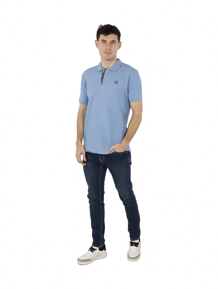Hombre vistiendo una playera polo de color azul claro con cierre frontal y manga corta.