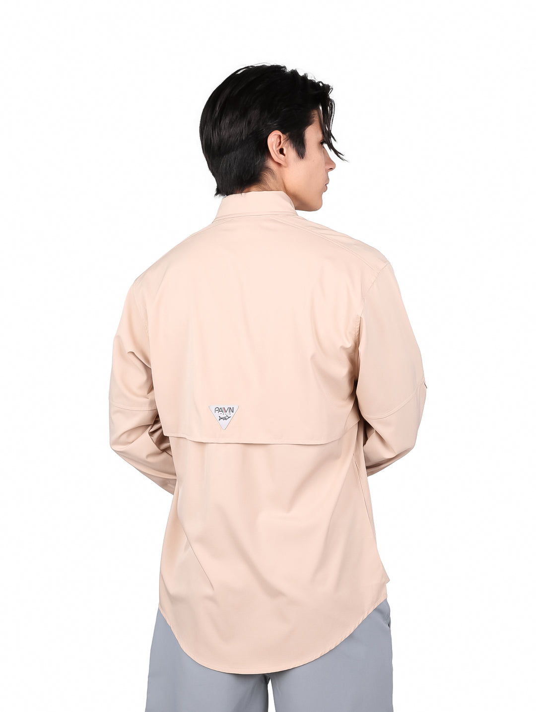 Hombre vistiendo una camisa color beige de manga larga con dos bolsillos frontales.