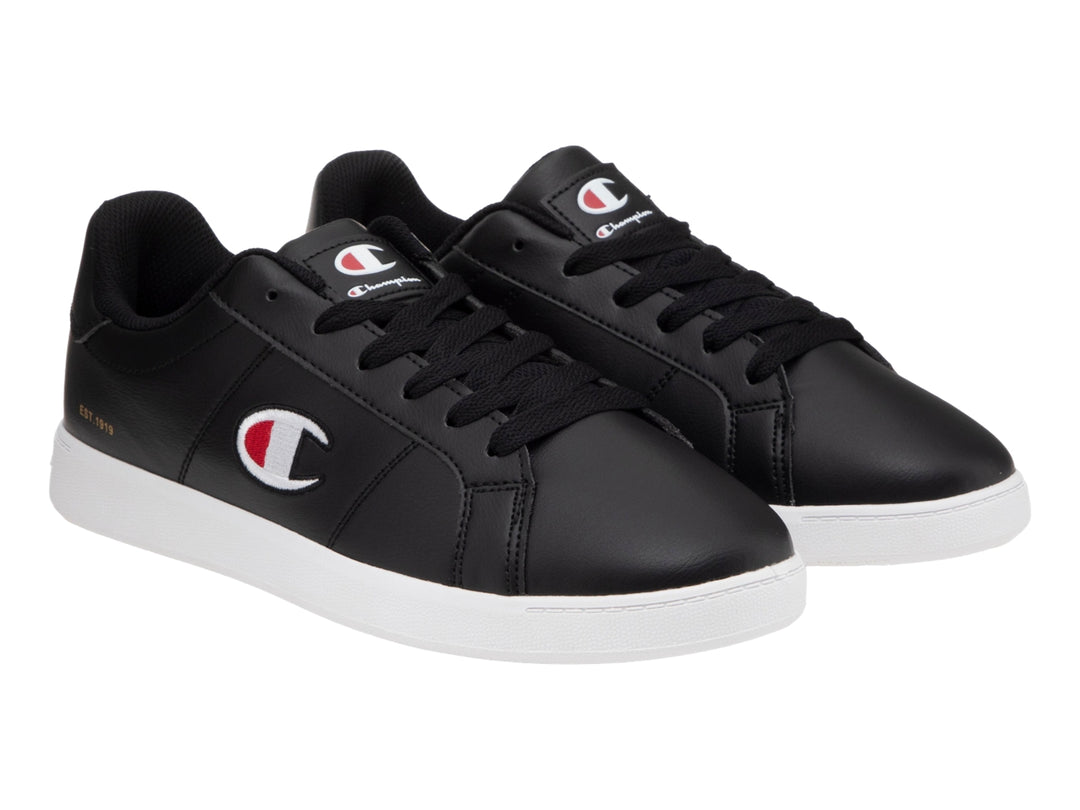 Tenis Champion color negro con suela blanca y logotipo lateral en blanco y rojo.