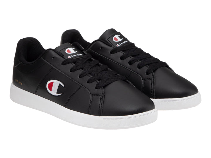 Tenis Champion color negro con suela blanca y logotipo lateral en blanco y rojo.
