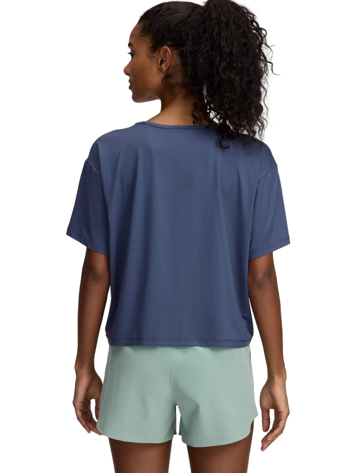Mujer vistiendo camiseta deportiva azul marino y shorts gris claro de Under Armour.