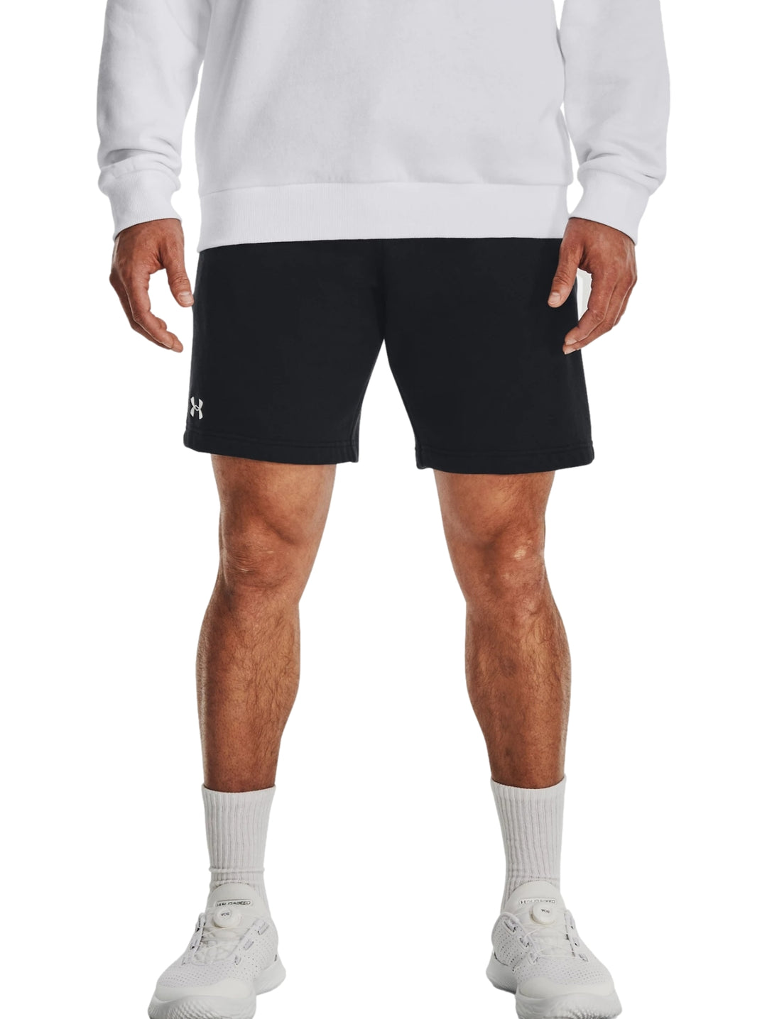Hombre vistiendo shorts deportivos negros de Under Armour con logo blanco.