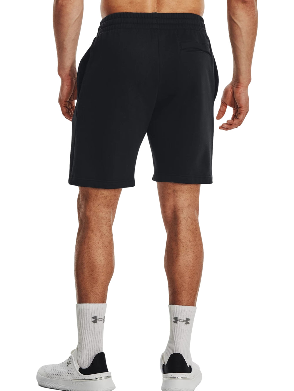Hombre vistiendo shorts deportivos negros de Under Armour con logo blanco.