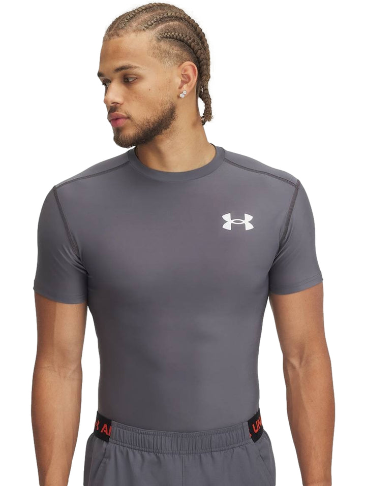 Hombre vistiendo una camiseta de compresión gris de manga corta marca Under Armour.