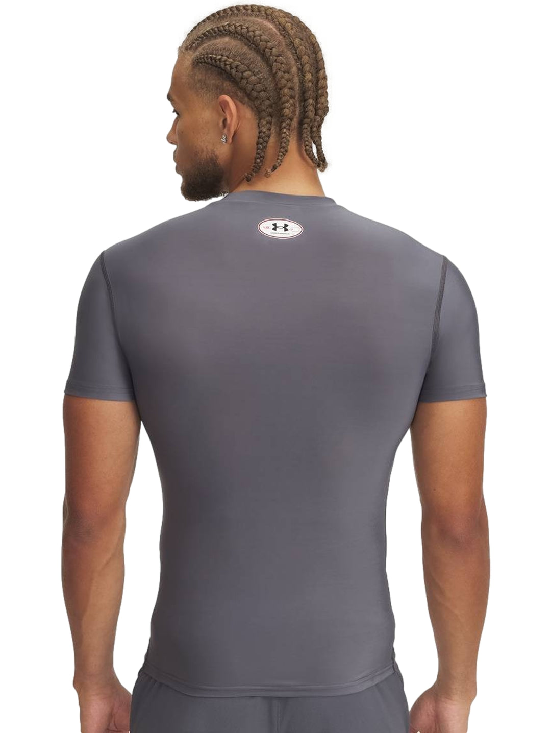 Hombre vistiendo una camiseta de compresión gris de manga corta marca Under Armour.