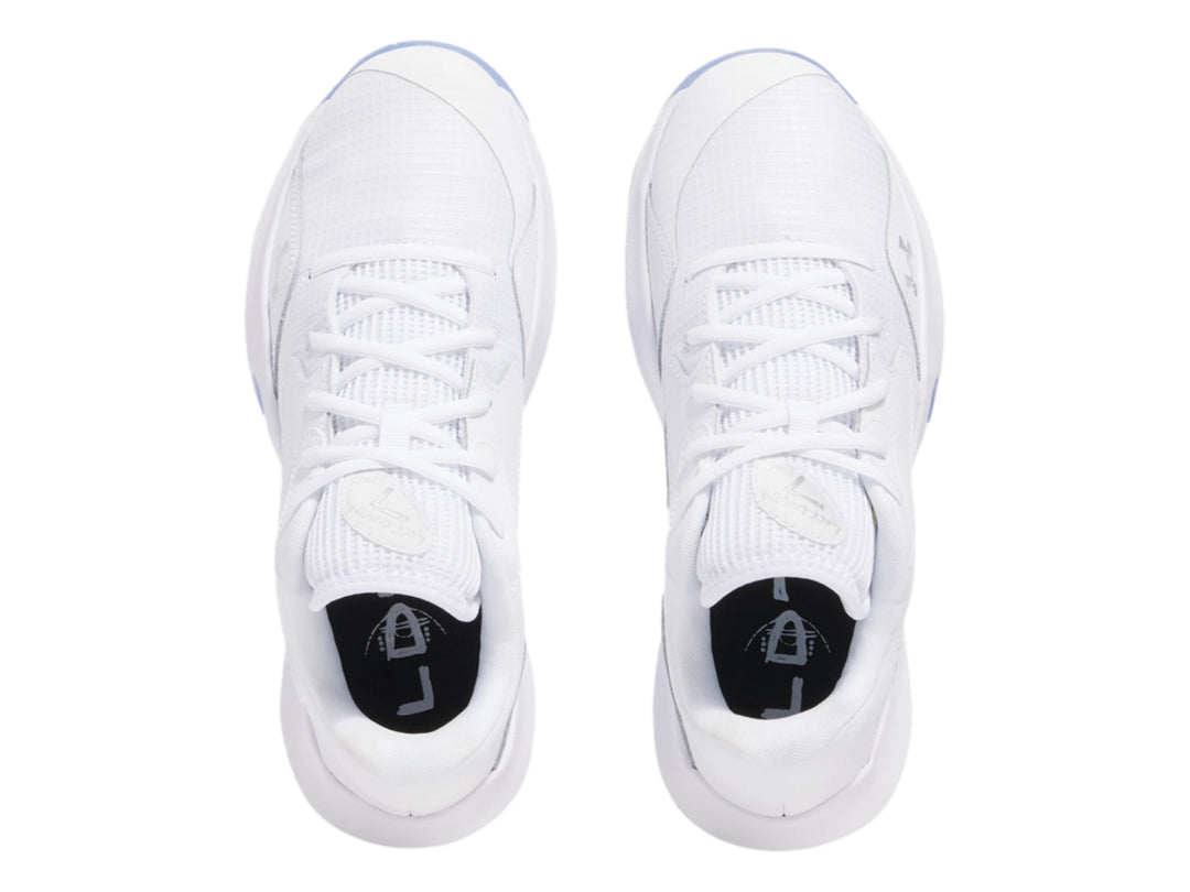 Tenis de baloncesto Under Armour Lockdown 7 Low en color blanco con detalles plateados y suela translúcida.