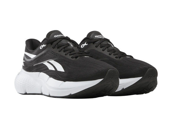 Tenis deportivos Reebok color negro con suela blanca y detalles laterales blancos.