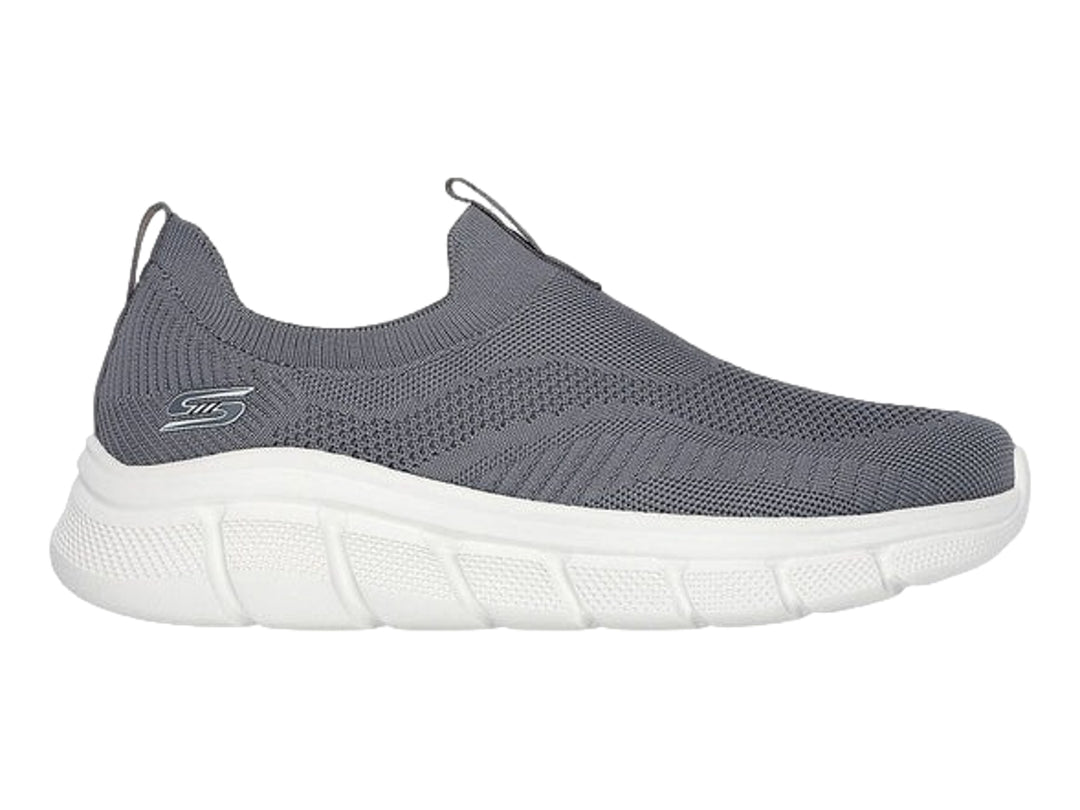 Tenis Skechers color gris oscuro con suela blanca, diseño slip-on de tejido flexible.