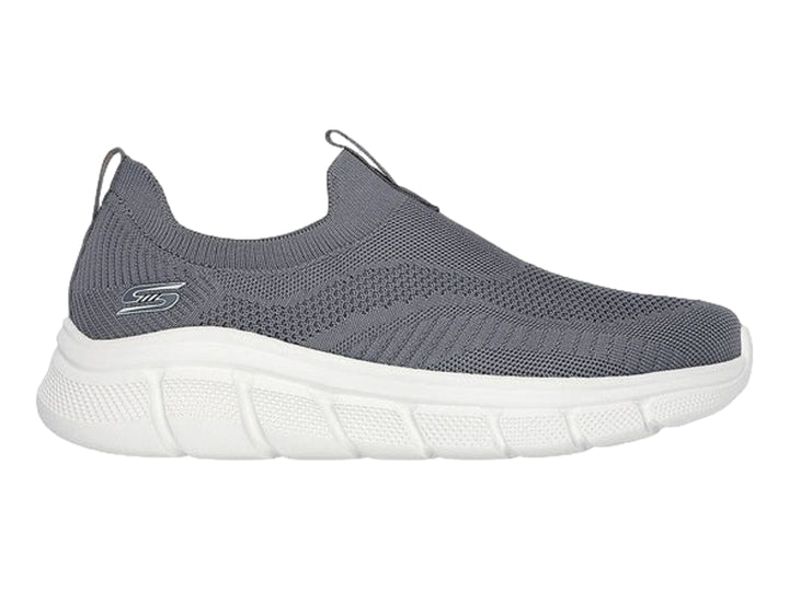 Tenis Skechers color gris oscuro con suela blanca, diseño slip-on de tejido flexible.