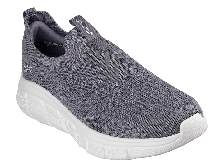 Tenis Skechers color gris oscuro con suela blanca, diseño slip-on de tejido flexible.