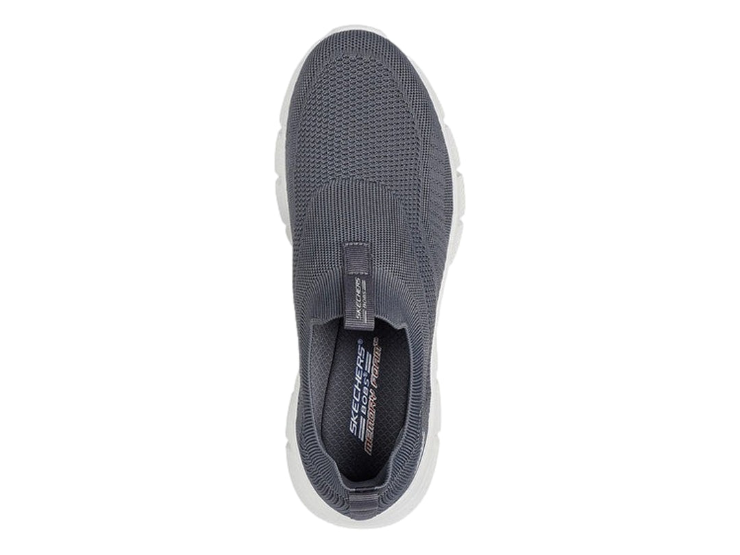 Tenis Skechers color gris oscuro con suela blanca, diseño slip-on de tejido flexible.