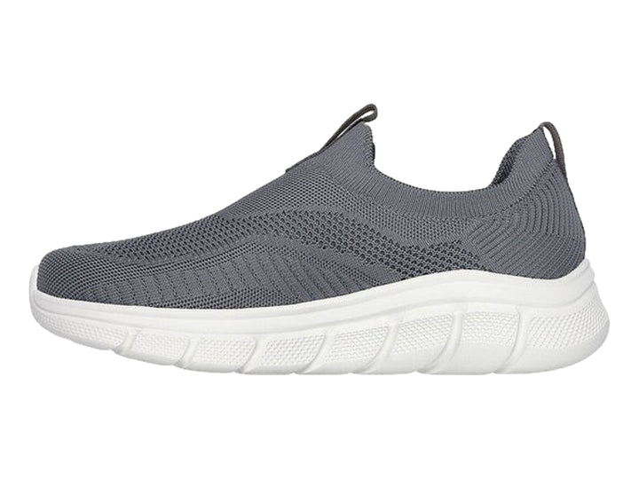 Tenis Skechers color gris oscuro con suela blanca, diseño slip-on de tejido flexible.