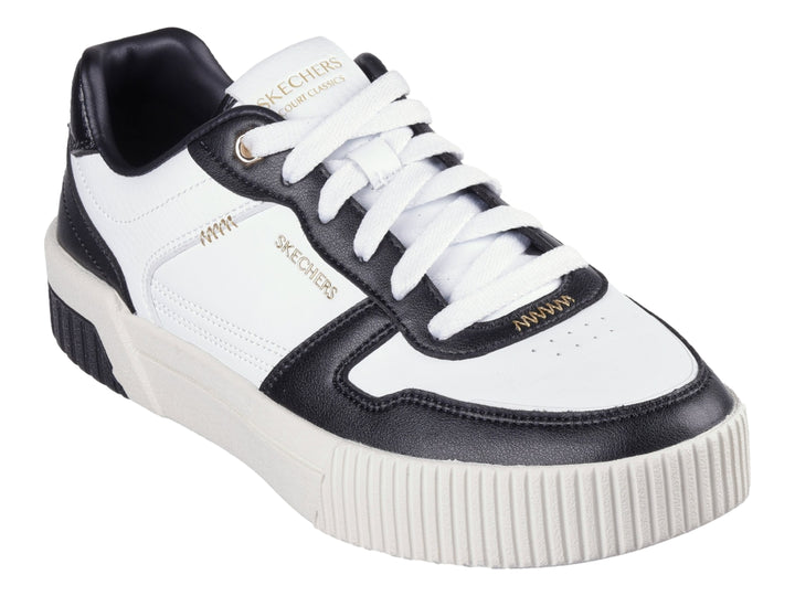 Tenis Skechers blancos con detalles en negro y suela blanca con talón negro.