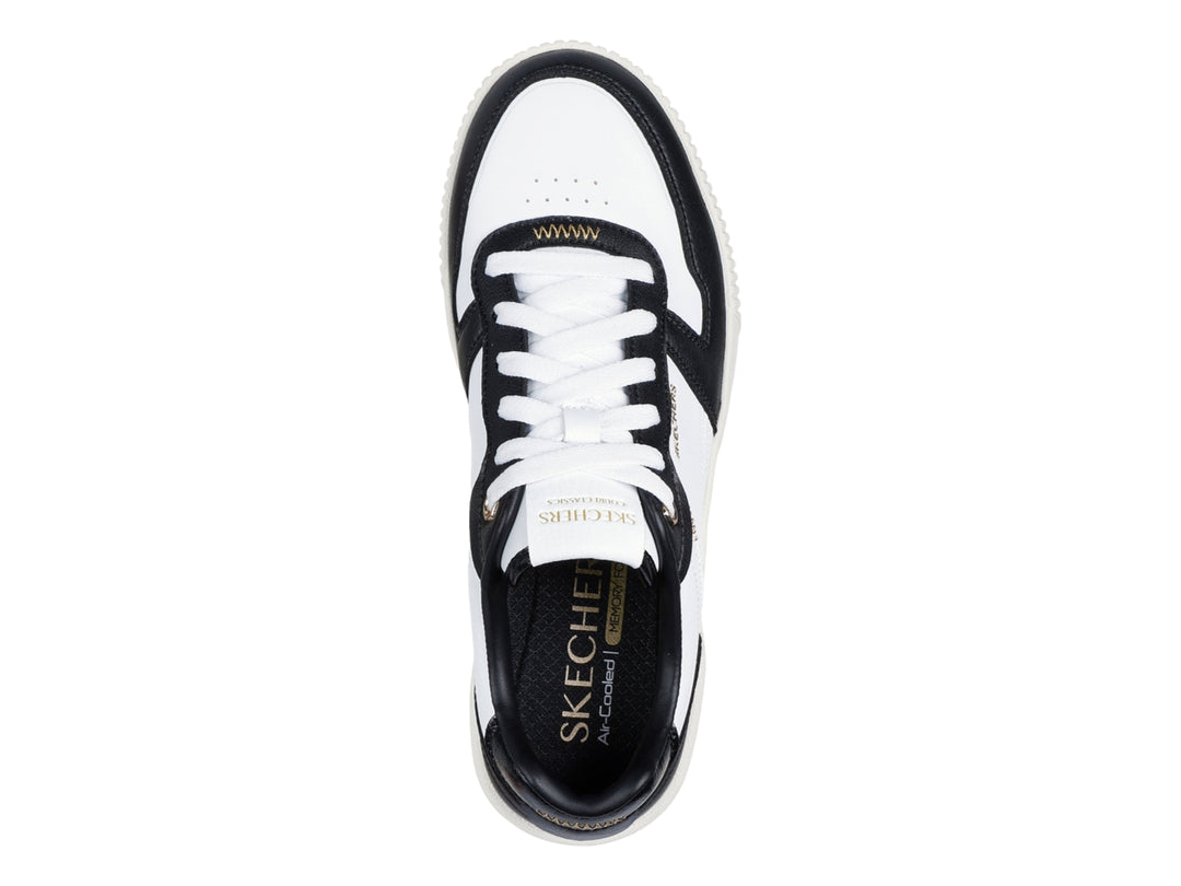Tenis Skechers blancos con detalles en negro y suela blanca con talón negro.