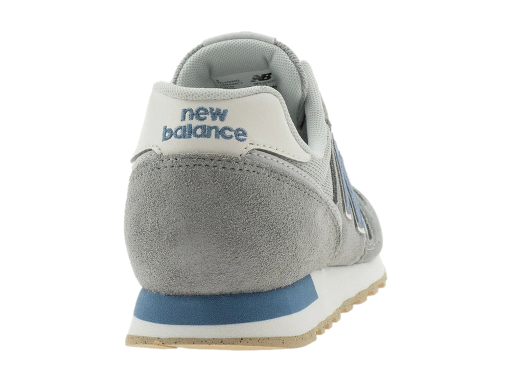 Tenis New Balance color gris con detalles en azul y suela beige.