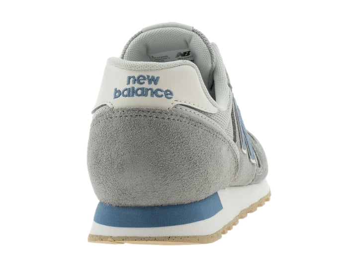 Tenis New Balance color gris con detalles en azul y suela beige.