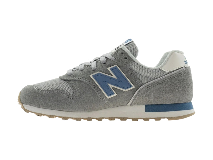 Tenis New Balance color gris con detalles en azul y suela beige.