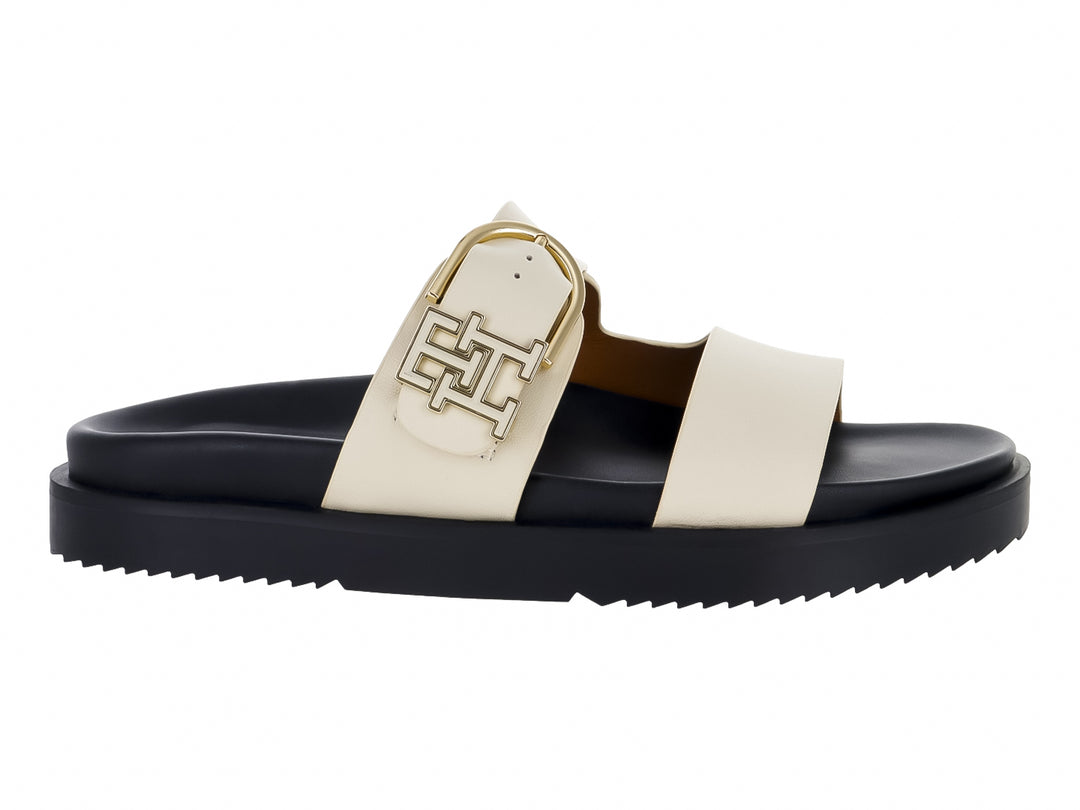 Sandalia mule Tommy Hilfiger de cuero con suela negra gruesa y correas blancas con hebilla dorada.