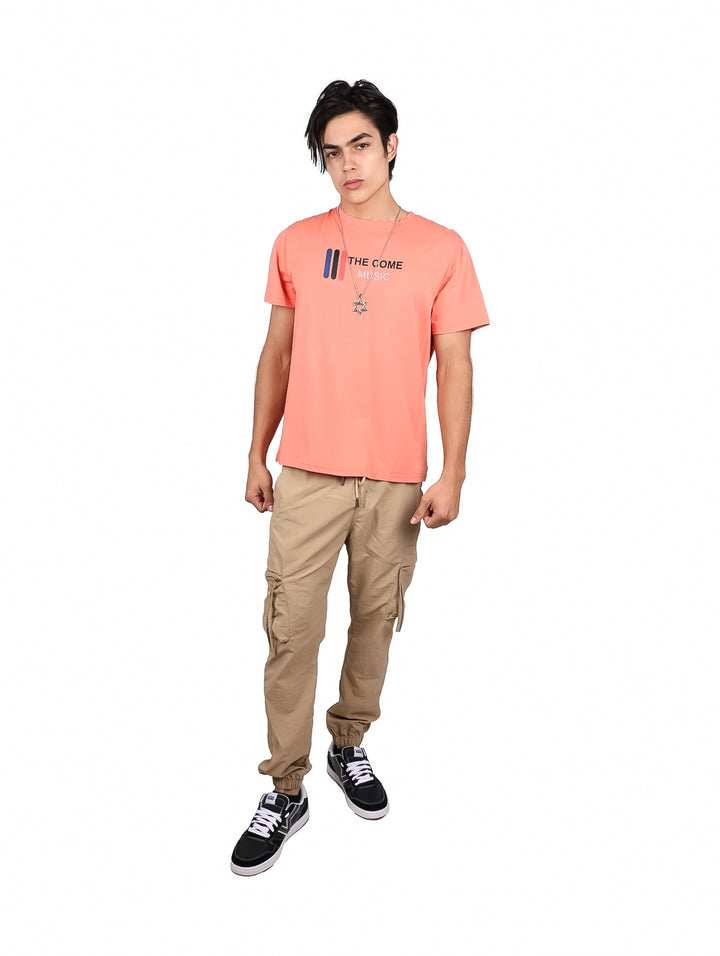 Hombre vistiendo playera color coral con estampado frontal y cuello redondo.