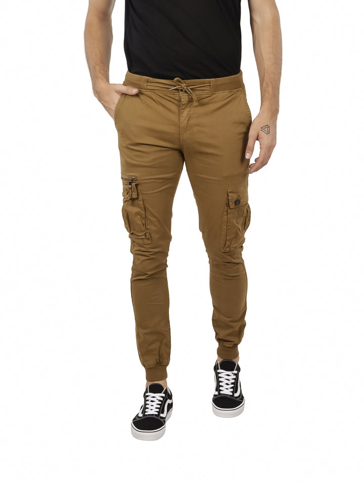 Hombre vistiendo pantalones jogger color camel con bolsillos cargo y tenis negros.