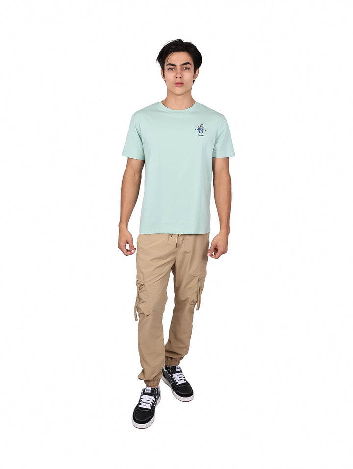 Hombre vistiendo una playera de manga corta color verde menta con un pequeño logo en el pecho.