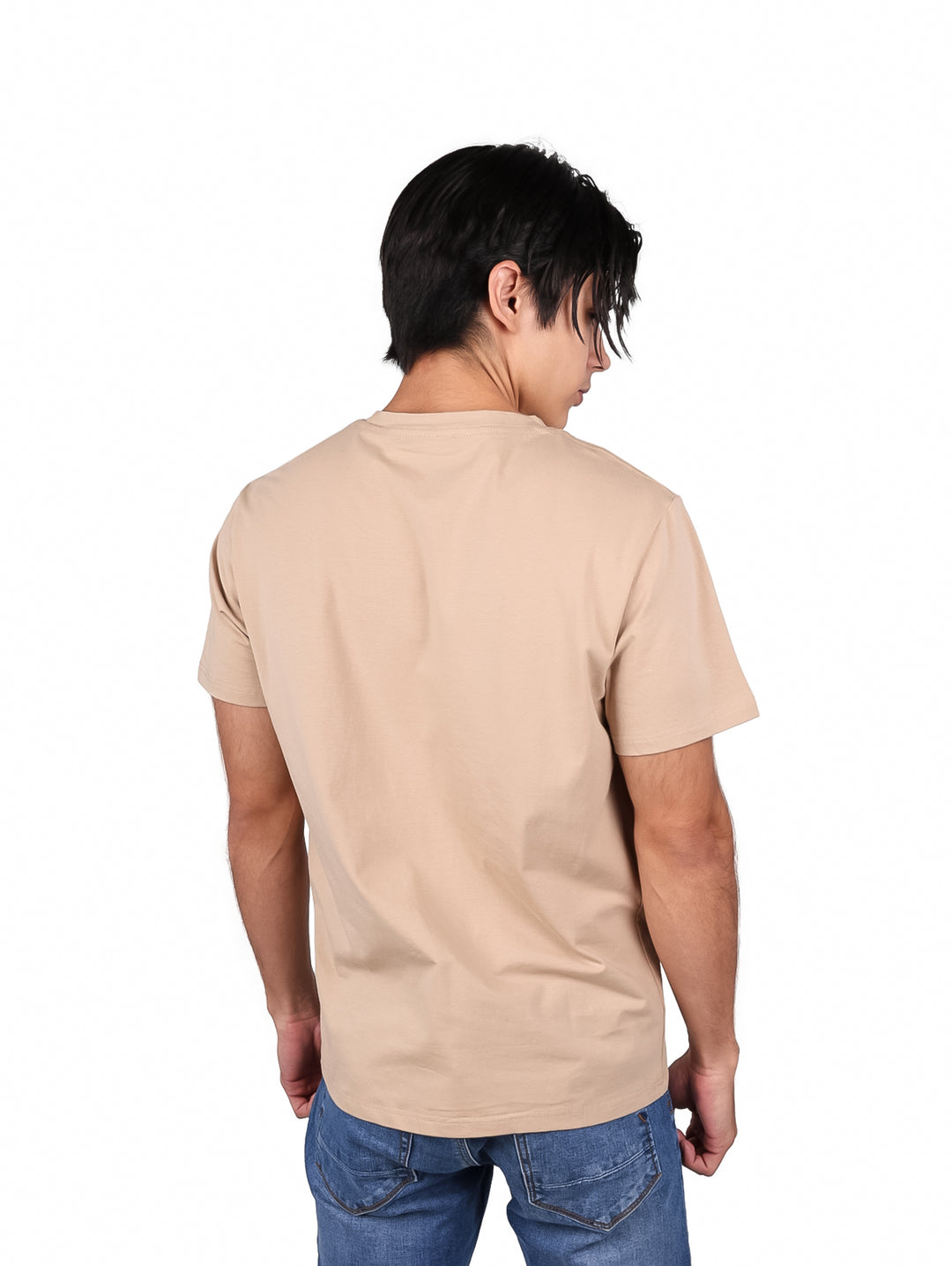 Hombre vistiendo una playera de manga corta color café con un pequeño logo en el pecho.