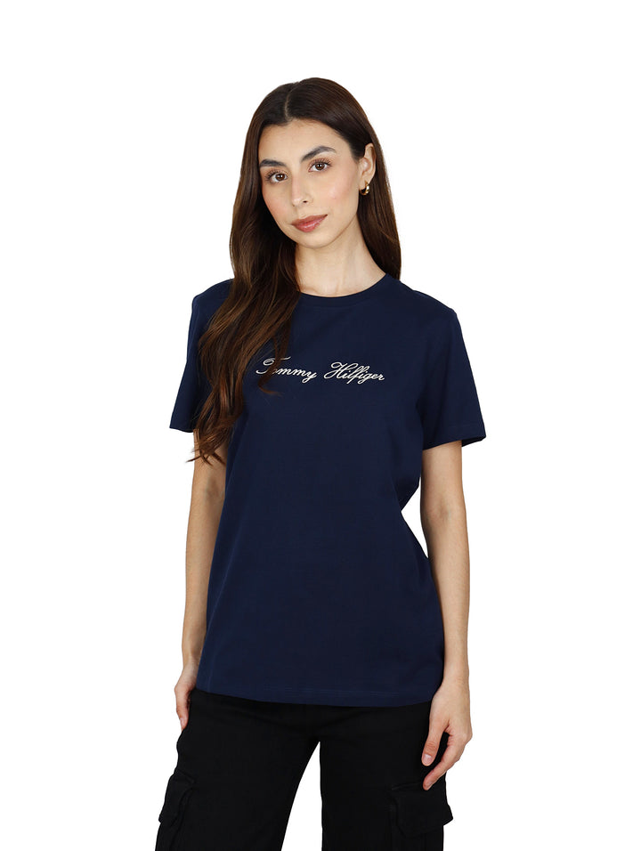 Mujer vistiendo playera azul marino de manga corta con logotipo de Tommy Hilfiger en el pecho.