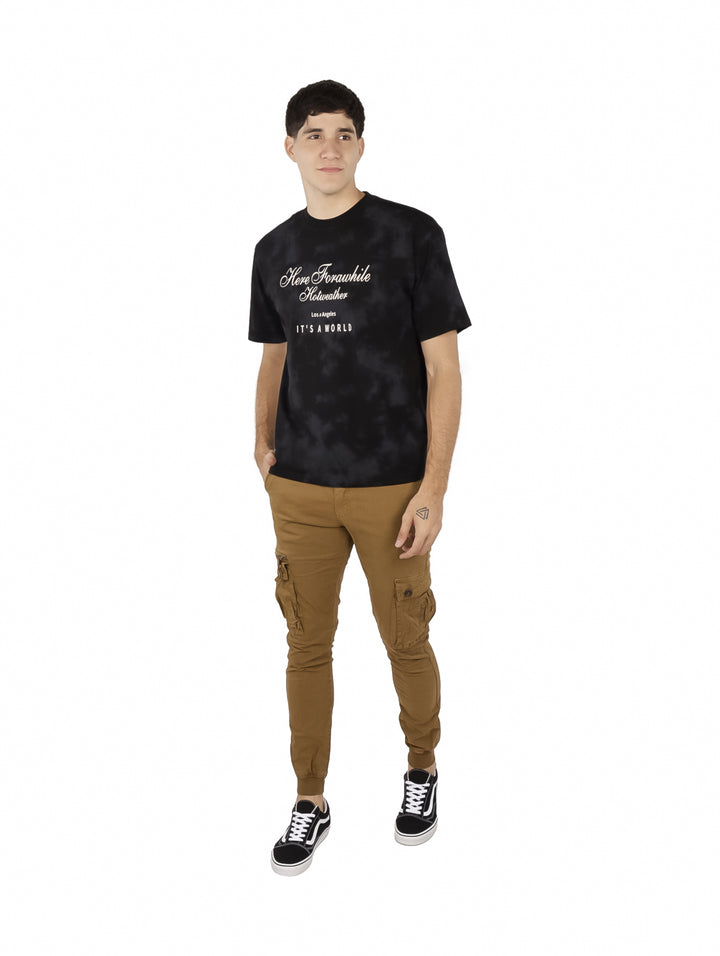 Hombre vistiendo playera oversize color negro con efecto tie-dye y estampado blanco en el pecho.