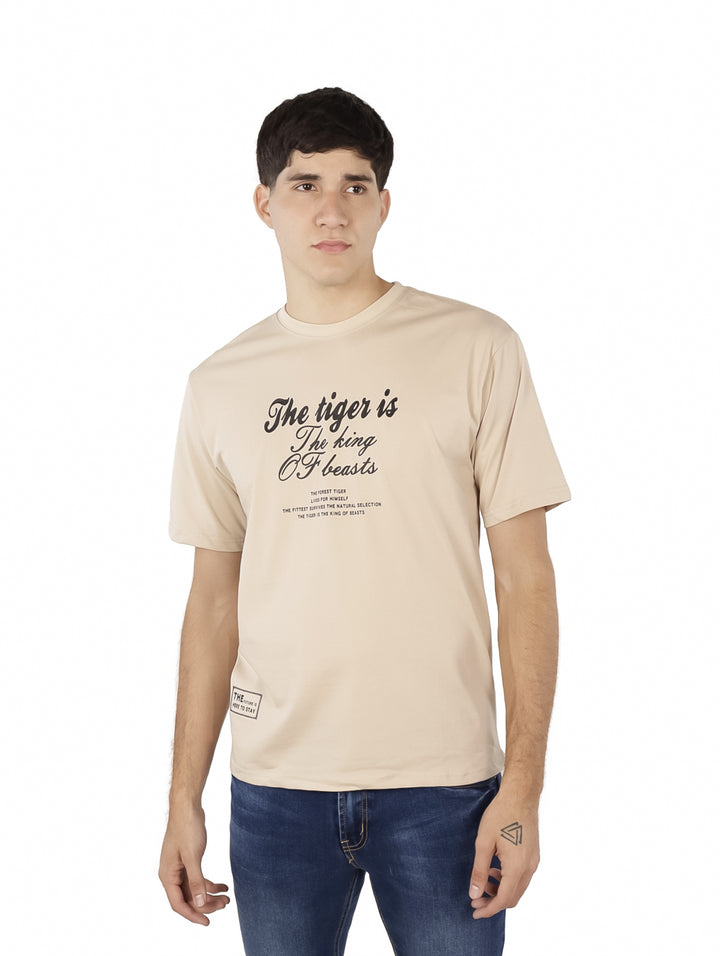 Hombre vistiendo playera oversize color khaki con estampado de texto en negro en el pecho.