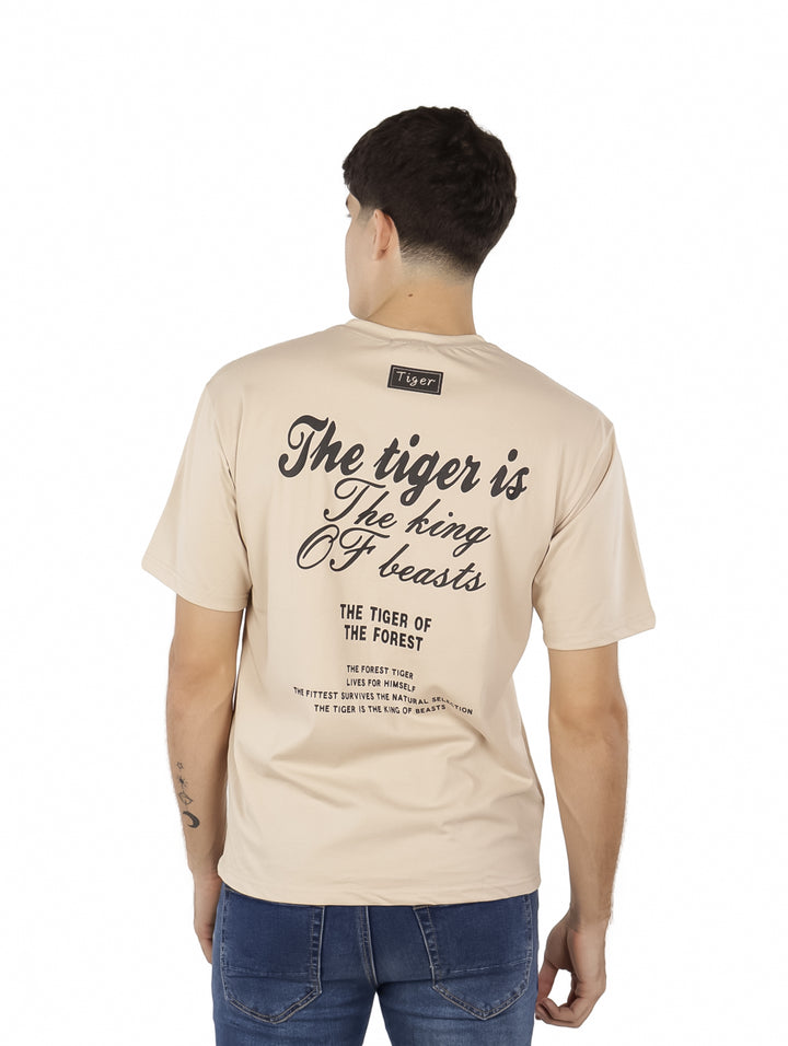 Hombre vistiendo playera oversize color khaki con estampado de texto en negro en el pecho.