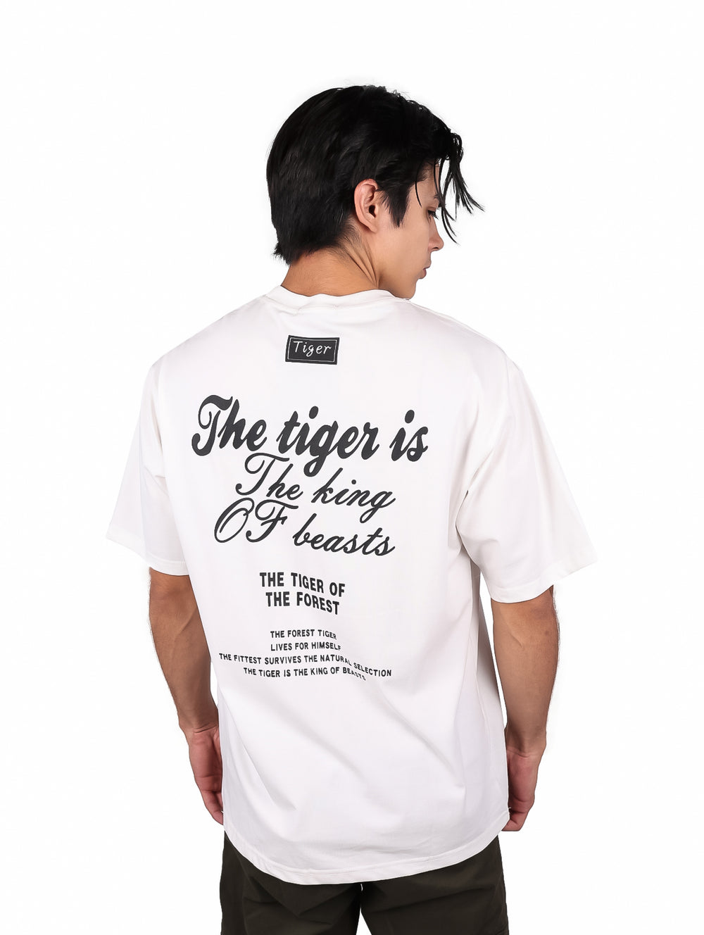 Hombre vistiendo playera blanca oversize de manga corta con estampado de texto negro en el pecho.