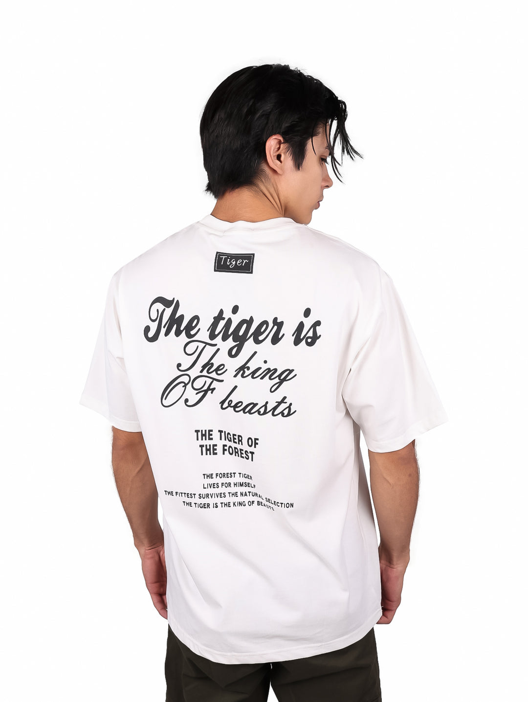 Hombre vistiendo playera blanca oversize de manga corta con estampado de texto negro en el pecho.