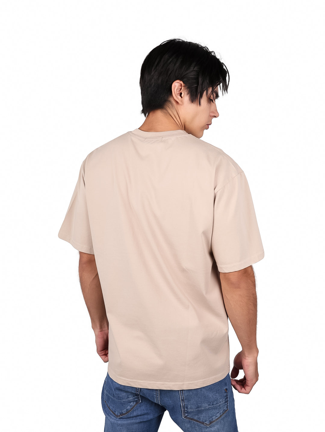 Hombre vistiendo playera oversize color khaki con texto impreso en la parte frontal.