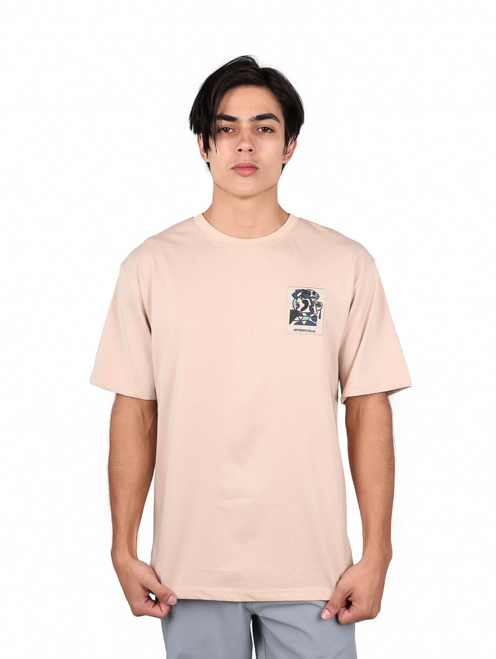 Hombre modelando una playera oversize color khaki de manga corta con un detalle gráfico en el pecho.