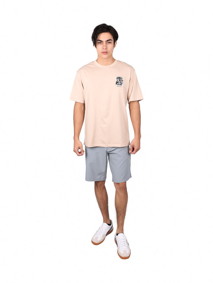 Hombre modelando una playera oversize color khaki de manga corta con un detalle gráfico en el pecho.