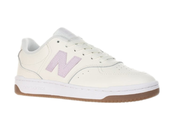 Tenis New Balance color blanco hueso con logotipo morado y suela color café.
