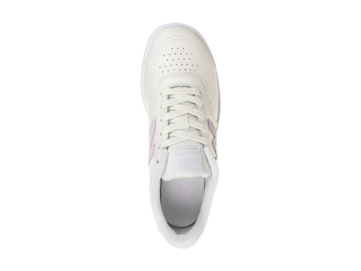 Tenis New Balance color blanco hueso con logotipo morado y suela color café.
