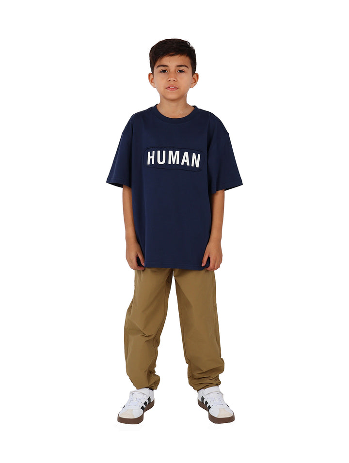 Niño vistiendo camiseta azul marino de manga corta con la palabra HUMAN impresa en letras blancas en el pecho.