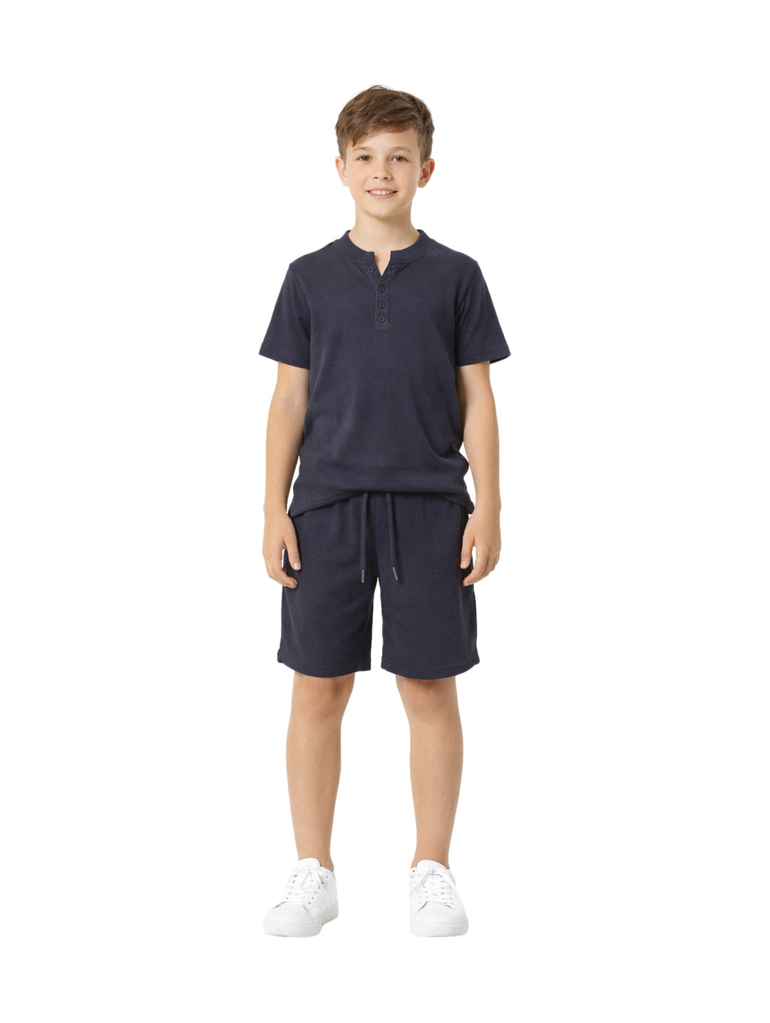 Conjunto de ropa para niño compuesto por camisa gris oscuro de manga corta y short a juego con tenis blancos.