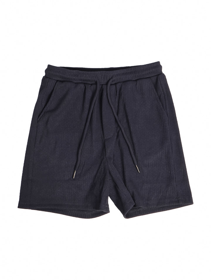 Conjunto de ropa para niño compuesto por camisa gris oscuro de manga corta y short a juego con tenis blancos.