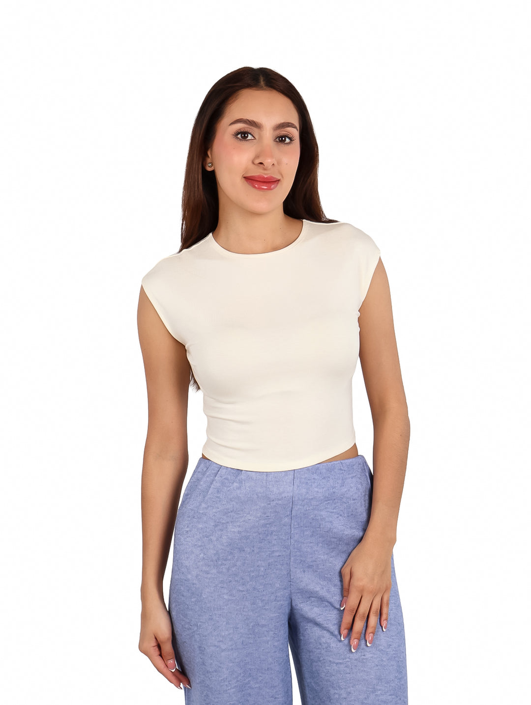 Mujer vistiendo un crop top blanco sin mangas y pantalones azules.